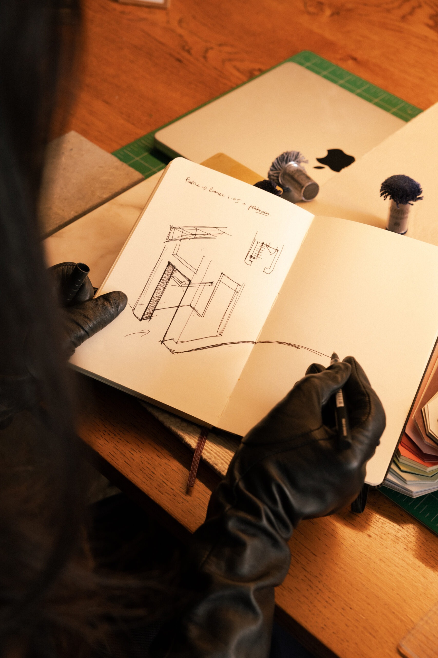 Interior designer's hand sketching room layout in open notebook with material samples in background